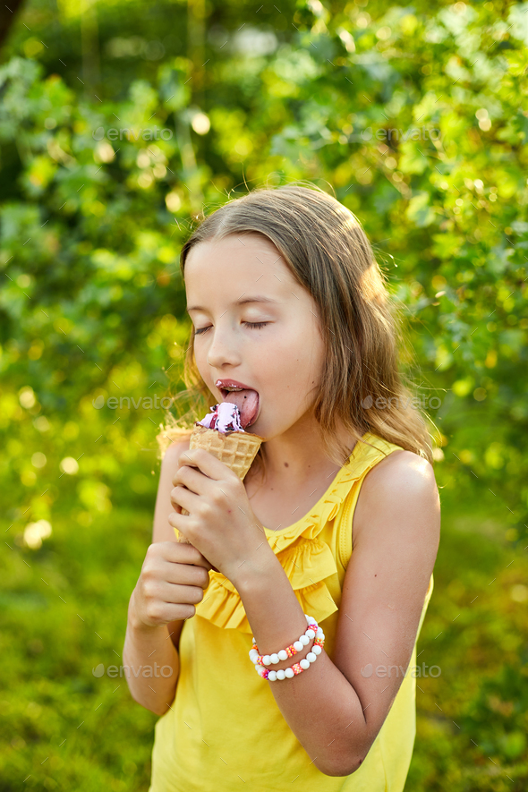 Happy girl with braces eating italian ice cream cone smiling while